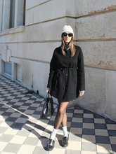 a lady wears a black coat with black loafers